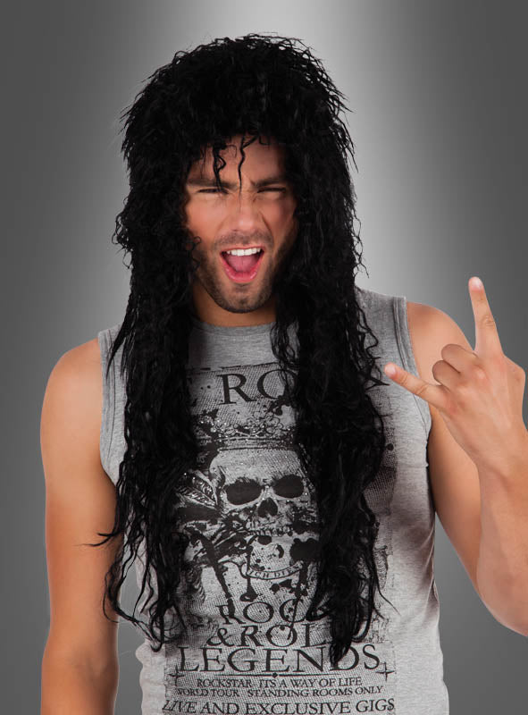 Ein Mann mit einer schwarzen „Rocker Langhaarperücke“ und einem ärmellosen Shirt mit Totenkopf-Motiv, der vor einem grauen Hintergrund die Rocker-Geste macht und zwinkert – der perfekte Look für jede 80er-Jahre-Party.