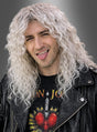 Eine Person mit langen, lockigen, platinblonden Haaren, die zu einer „Rocker-Perücke“ mit weißen Strähnen frisiert sind, trägt eine schwarze Lederjacke und ein Bon-Jovi-T-Shirt, streckt die Zunge heraus und posiert vor einem grauen Hintergrund.