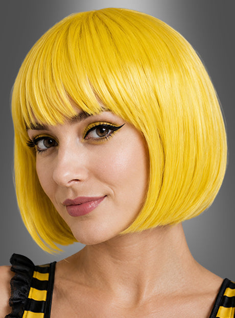 Mit der „Hochwertige Bobfrisur Helene gelb“ – einer kurzen, glatten, leuchtend gelben Perücke – und passendem gelbem Augen-Make-up blickt eine Person vor einem grauen Hintergrund in die Kamera und verkörpert damit perfekt den ausgefallenen Stil eines 80er-Jahre-Kostüms.