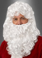 Eine Person, die eine weiße Perücke mit Bart trägt und ein rotes Weihnachtsmannkostüm anhat, vor einem neutralen grauen Hintergrund.