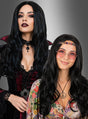 Zwei Frauen stehen Seite an Seite in auffälligen Partykostümen; die eine trägt ein Gothic-Vampir-Kostüm, kombiniert mit der vielseitigen Langhaarperücke mit Wellen in Schwarz, während die andere ein Retro-Hippie-Outfit trägt, komplett mit runder Brille, einer Halskette mit Peace-Zeichen und derselben mühelos schicken vielseitigen Langhaarperücke mit Wellen in Schwarz – beide tragen langes schwarzes Haar.