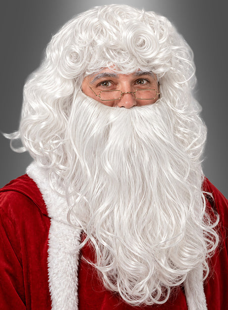 Eine Person, die den „Deluxe Weihnachtsmann-Bart mit Perücke“, eine Brille und ein rotes Samt-Nikolauskostüm mit weißer Borte trägt, posiert vor einem grauen Hintergrund.