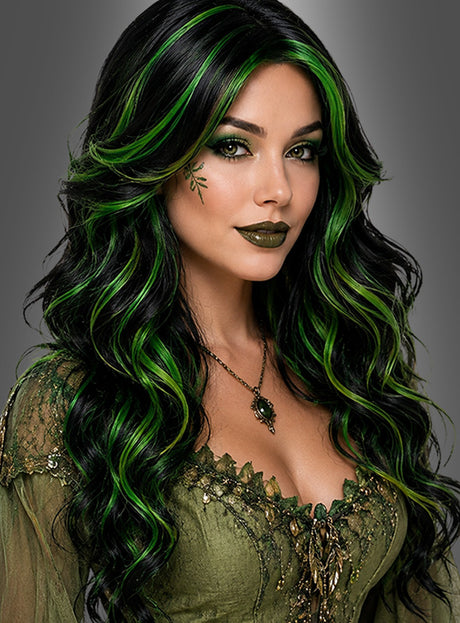 Eine Frau mit langen, welligen schwarz-grünen Haaren, gestylt mit der Langhaar-Perücke „Ivy mit Locken schwarz-grün“, grünem Lidschatten und Lippenstift, die ein grünes Spitzenkleid und eine Halskette mit Blattmotiv trägt und vor einem grauen Hintergrund posiert – die perfekte Inspiration für alle, die auf der Suche nach einem Hexen-Kostüm sind.