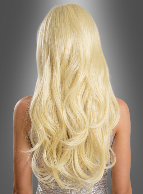 Eine Person mit langen, welligen blonden Haaren, von hinten gesehen, die ein funkelndes silbernes Oberteil vor einem grauen Hintergrund mit Farbverlauf trägt – hier wird die „Deluxe Langhaarperücke mit Wellen blond“ präsentiert, die mühelos natürlich und elegant wirkt.