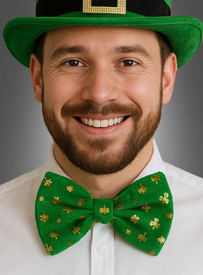 Ein Mann mit einem grünen Hut und der St. Patrick’s Day-Fliege mit Kleeblättern – einer eleganten großen grünen Samtfliege mit goldenen Kleeblattmustern –, der vor einem grauen Hintergrund in die Kamera lächelt; perfekt als St. Patrick’s Day-Kostüm oder als stilvolles Kleeblatt-Accessoire.