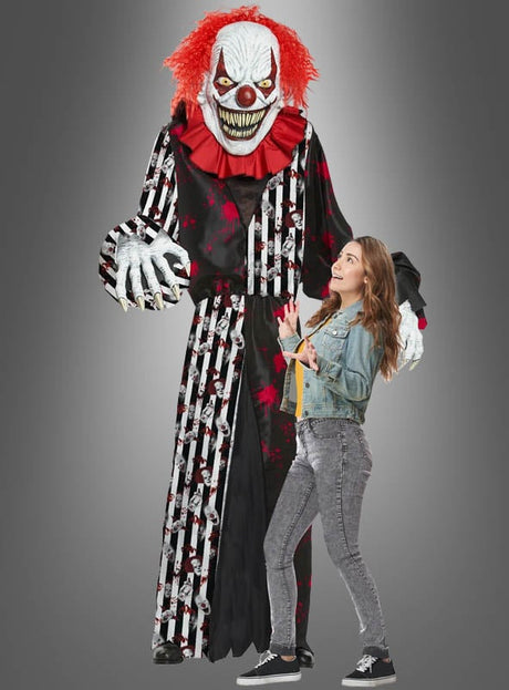 Eine imposante Gestalt im „Gigantischen Horrorclown-Kostüm oder Deko, ca. 240 cm“ – komplett mit wildem rotem Haar und messerscharfen Zähnen – ragt bedrohlich über einer erschrockenen jungen Frau in Freizeitkleidung vor einem grauen Hintergrund empor und ist damit die perfekte Halloween-Dekoration, um eine gruselige Szene zu schaffen.