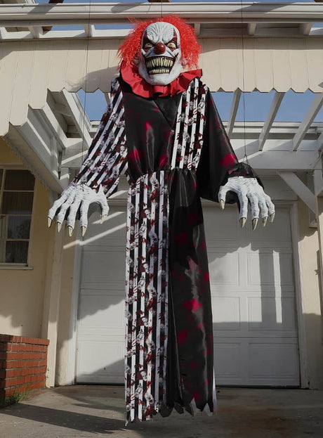 Ein gigantisches Horrorclown-Kostüm oder eine Dekoration (ca. 240 cm) mit roten Haaren, großen Krallen und einem auffälligen schwarz-rot gemusterten Gewand steht imposant vor einer Hausgarage – eine perfekte Halloween-Dekoration für alle, die einen furchterregenden Blickfang schaffen möchten.