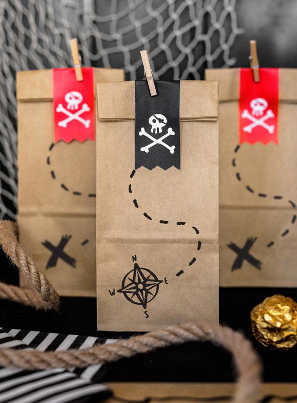 Im Set sind sechs braune Papier-„Geschenktüten Piratenparty“ enthalten, die jeweils mit Piratenmotiven wie Totenkopf-Aufklebern und Schatzkarten-Motiven verziert sind. Im Vordergrund sind Seile und goldverpackte Schokoladenmünzen zu sehen – diese Tüten eignen sich ideal als umweltfreundliche Geschenktüten für eine aufregende Piratenparty zum Kindergeburtstag.