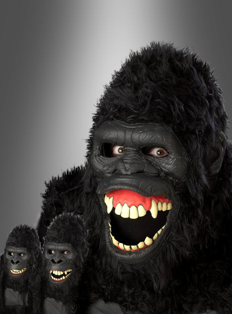 Eine Person, die eine schwarze „Gorilla Maske beweglich Ani-Motion“ mit offenem, beweglichem Kiefer trägt, posiert neben zwei identischen, kleineren Gorillafiguren vor einem grauen Hintergrund mit Farbverlauf.