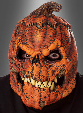 Eine Person, die die Halloween-Maske „beweglicher Kürbis Ani-Motion“ trägt, mit großen gelben Zähnen, strukturierter orangefarbener Schale und hohlen Augen, vor grauem Hintergrund.
