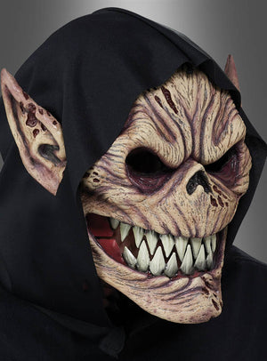 Eine Person, die eine „Kobold Dämon Ani-Motion“-Maske mit scharfen Zähnen, spitzen Ohren und einer schwarzen Kapuze trägt, vor einem schlichten grauen Hintergrund.
