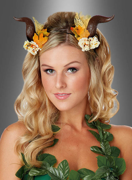 Eine Frau mit langen blonden Haaren trägt die „Fantasy Hörner für Feenkostüme“, die mit herbstfarbenen Blumen und einer grünen Blattgirlande vor grauem Hintergrund verziert sind und so einen bezaubernden Feenkostüm-Look schaffen.