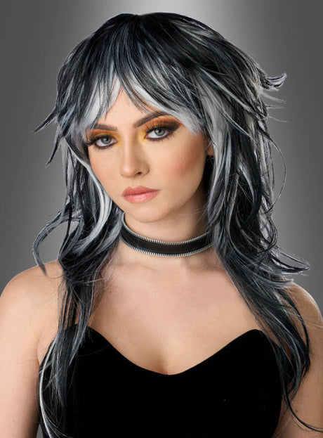 Eine Frau mit langen, welligen schwarzen Haaren, die zu einer schwarz-grauen, gestuften Gothic-Perücke gestylt waren, mit dramatischem Make-up, einem schwarzen Oberteil und einer Metall-Choker-Halskette posierte vor einem grauen Hintergrund mit Farbverlauf.