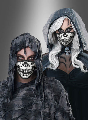 Zwei Personen tragen zerfetzte, dunkle Kostüme mit Kapuze und Gesichtsmasken mit Totenkopfmuster – die eine mit langen weißen Haaren, die andere mit kurzen Haaren. Ihre Baumwoll-Gesichtsmaske „Skelett Glow in the Dark“ leuchtet in der Dunkelheit sanft und verstärkt so ihr gespenstisches und unheimliches Aussehen.