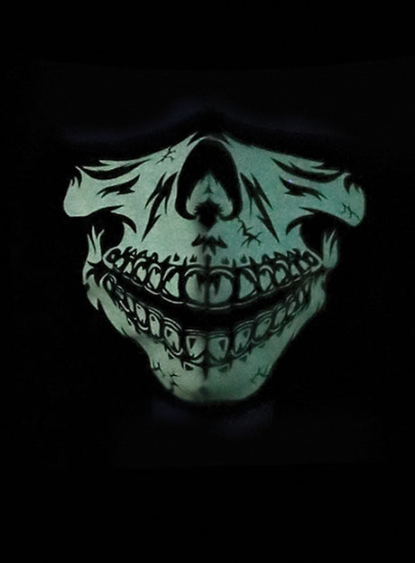 Auf schwarzem Hintergrund ist ein leuchtend grüner Totenkopf mit übertrieben großen Zähnen und Rissen abgebildet, der an die „Baumwolle Gesichtsmaske Skelett Glow in the Dark“ erinnert und so einen unheimlichen Effekt erzeugt.