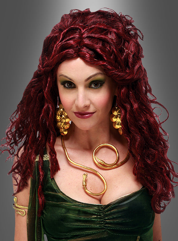 Eine Frau mit lockigem rotem Haar, gestylt mit der „Medusa-Perücke mit Locken & Dreads“, trägt ein grünes Kleid, goldene Ohrringe und eine schlangenförmige Halskette und posiert vor einem grauen Hintergrund mit Farbverlauf – perfekt, um dein Medusa-Kostüm zu vervollständigen.