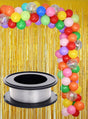 Vor einem schimmernden Hintergrund mit goldenen Fransen steht ein farbenfroher Ballonbogen (Ballongirlande), während im Vordergrund eine Rolle „Angelschnur Deko Befestigung 100 m“ gut sichtbar platziert ist – ideal, um Ihrer Partydekoration eine raffinierte Note zu verleihen.