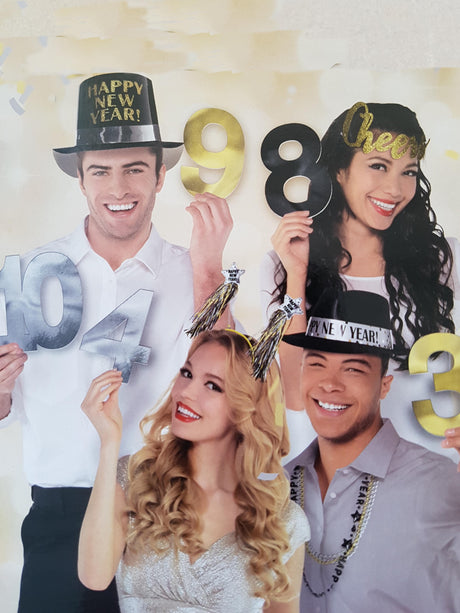 Vier Personen mit festlichen Hüten, die die „Fotobox Zahlen“ in Gold und Silber (Silvester-Zahlen) in den Händen halten und mit einem Lächeln und Dekorationen vor einem hellen Hintergrund Silvester feiern – perfekt, um mit diesem lustigen Party-Accessoire stilvolle Erinnerungen festzuhalten.