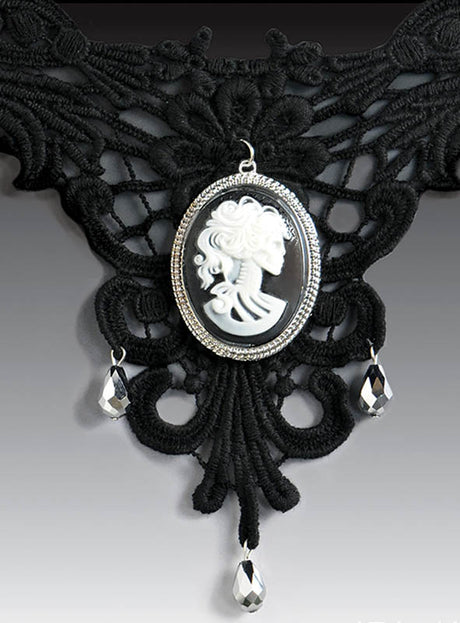 Gothic-Halsschmuck „Cameo mit Skelettgesicht“ – ein schwarzer Choker aus Spitze mit einem zentralen Cameo-Anhänger in Form eines Skelettgesichts, der durch drei herabhängende Kristalltropfen akzentuiert wird.