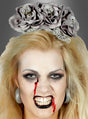 Eine Frau mit blassem Make-up, Kunstblut auf der Nase, schwarzem Lippenstift und dem Halloween-Kopfschmuck mit grauem Totenkopf – einem atemberaubenden, mit grauen Totenkopf-Verzierungen geschmückten Blumenkopfschmuck – starrt die Kamera grimmig an – perfekt, um an diesem Halloween deine innere Skelett-Diva zum Vorschein zu bringen.