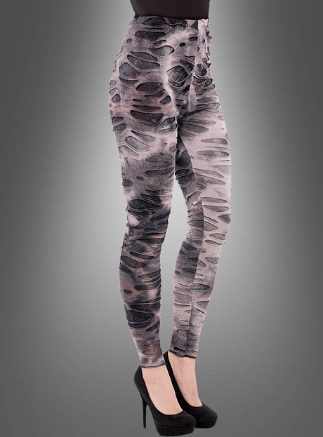 Eine Person trägt „Fetzige Zombie-Leggings“ – graue Leggings mit hoher Taille, im Used-Look und mit schwarzen Mustern –, kombiniert mit schwarzen Stöckelschuhen, und posiert vor einem schlichten grauen Hintergrund. So entsteht eine auffällige Option für ein Halloween-Kostüm oder ein ausgefallener Lagenlook für deinen Stil.