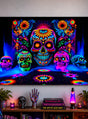 Als auffälliger Blickfang hängt das XXL-UV-Stoffbanner „Tag der Toten“ (250 × 350 cm, waschbar) mit einem leuchtenden Neon-Totenkopf-Motiv über einem Tisch, der mit einem Totenkopf, Topfpflanzen, einer Lavalampe, Büchern und einer dekorativen Hand geschmückt ist – die perfekte Schwarzlicht-Dekoration für Ihre Wand.