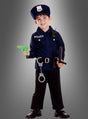 Ein kleines Kind, das das „Polizei-Kinderkostüm- und Waffen-Set“ trägt, lächelt vor einem grauen Hintergrund und hält eine grüne Spielzeugpistole sowie einen Schlagstock in der Hand, an dessen Gürtel Handschellen befestigt sind.