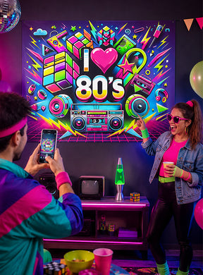 Zwei Personen in Retro-Outfits aus den 1980er Jahren posieren neben einer „I love 80s“-Neonreklame, umgeben von klassischer Partydekoration wie einer Boombox, einer Lavalampe, Rubik-Würfeln, Luftballons und farbenfroher Schwarzlicht-Dekoration. Das große, waschbare UV-Stoffbanner „80er Jahre“ (150 x 185 cm) als Partydekoration sorgt für einen zusätzlichen Farbtupfer und macht dies zur ultimativen Kulisse für eine unvergessliche 80er-Jahre-Party.