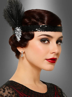 Eine Frau in einem von den 1920er Jahren inspirierten Outfit mit welligem Haar, auffälligem Make-up, verzierten Ohrringen und einem markanten Pailletten-Haarband im Stil der 20er Jahre als Accessoire zu ihrem Flapper-Kostüm posiert vor einem grauen Hintergrund mit Farbverlauf.