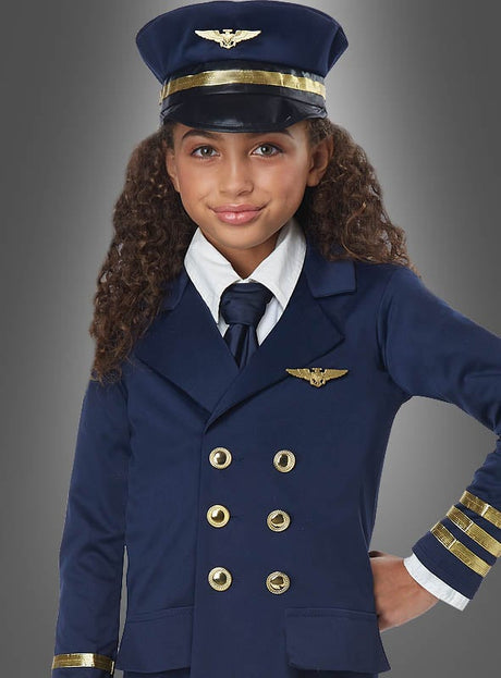 Ein junges Mädchen, das das „Flugzeugkapitän-Kostüm für Kinder“ trägt – eine marineblaue Pilotenuniform mit goldenen Knöpfen, einer Krawatte und einer passenden Mütze –, steht vor einem grauen Hintergrund.