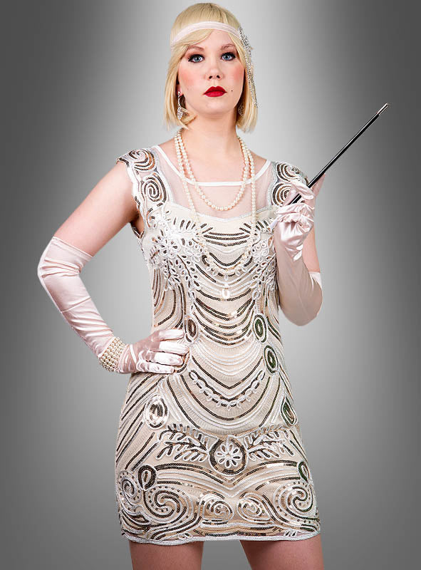 Vor einem grauen Hintergrund mit Farbverlauf steht eine Frau, die das „Luxuriöse Paillettenkleid Jessie“ trägt – ein glamouröses, von den 1920er Jahren inspiriertes Flapper-Kleid, das mit funkelnden Pailletten und Perlenstickereien verziert ist. Sie trägt dazu lange Handschuhe, Perlen und ein verziertes Stirnband und hält eine Zigarettenspitze in der Hand.