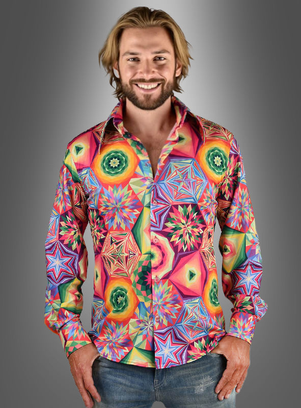 Ein Mann mit schulterlangen blonden Haaren trägt das „Funky Neon Hemd Herren“ mit leuchtenden Stern- und Wirbelmustern – perfekt für eine 70er-Jahre-Schlagerparty –, während er vor einem grauen Hintergrund mit Farbverlauf steht.