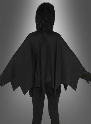 Eine Person in einem schwarzen Spinnen-Poncho für Kinder mit einem gezackten Umhang und einer pelzigen Kapuze, die mit dem Rücken zur Kamera vor einem grauen Hintergrund mit Farbverlauf steht – perfekt als Halloween-Kinderkostüm oder leuchtendes Spinnenkostüm für fantasievolles Spielen.