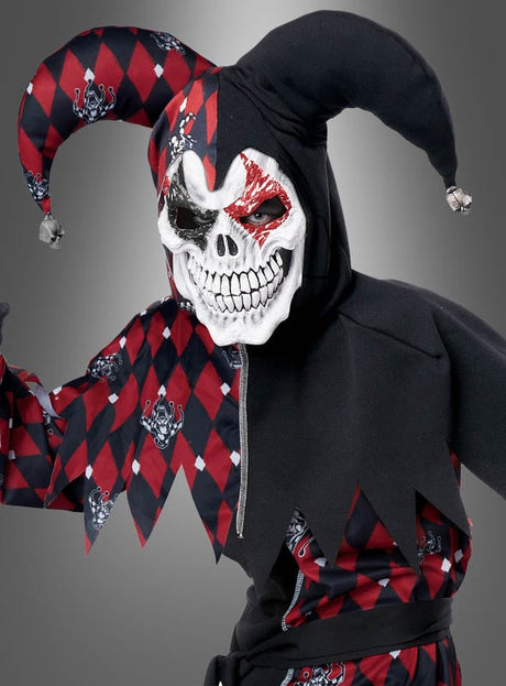 Eine Person, die das „Psycho Jester Hofnarr“-Kinderkostüm trägt – mit einem schwarz-rot-weißen Rautenmuster und einer gruseligen Totenkopfmaske –, steht vor einem grauen Hintergrund.