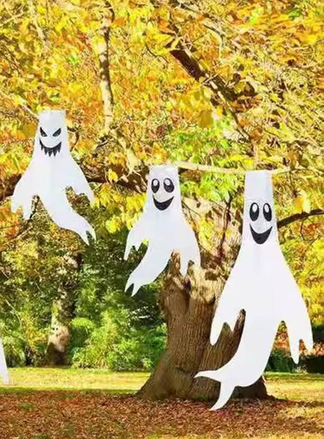 Drei Geisterfiguren mit unterschiedlichen Gesichtsausdrücken hängen an den Ästen eines mit Herbstlaub geschmückten Baumes und bilden so die perfekte Halloween-Dekoration für den Außenbereich. Diese bezaubernden „Geister-Windspiel 60 cm“-Gartendekofiguren setzen einen verspielten Akzent bei Ihrer Halloween-Geisterdekoration und verleihen jedem Außenbereich eine festliche Atmosphäre.