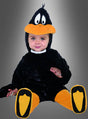 Ein Baby, das ein schwarz-gelbes Daffy-Duck-Baby-Entenkostüm trägt, sitzt vor einem grauen Hintergrund mit Farbverlauf und schaut in die Kamera.