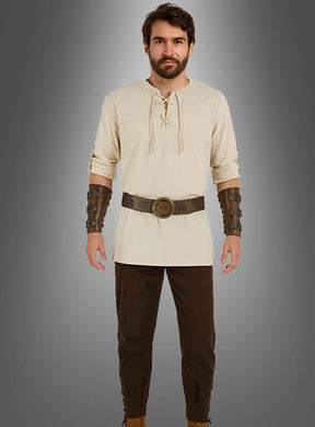 Ein Mann steht mit dem Blick nach vorne, gekleidet in das 5-teilige Mittelalter-Kostüm-Set für Herren – bestehend aus einer beigen Tunika, einer braunen Hose, einem breiten Gürtel und braunen Armschienen –, vor einem grauen Hintergrund mit Farbverlauf.