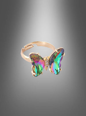 Ein verstellbarer Schmetterlingsring aus Glas mit einem großen, mehrfarbigen, schmetterlingsförmigen Edelstein steht im Mittelpunkt vor einem grauen Farbverlaufshintergrund und präsentiert eleganten Glasschmuck – perfekt als Modeschmuck für Damen.