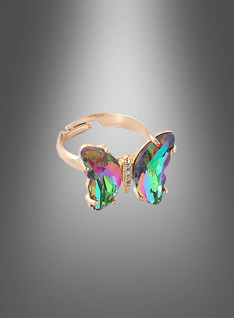 Ein verstellbarer Schmetterlingsring aus Glas mit einem großen, mehrfarbigen, schmetterlingsförmigen Edelstein steht im Mittelpunkt vor einem grauen Farbverlaufshintergrund und präsentiert eleganten Glasschmuck – perfekt als Modeschmuck für Damen.