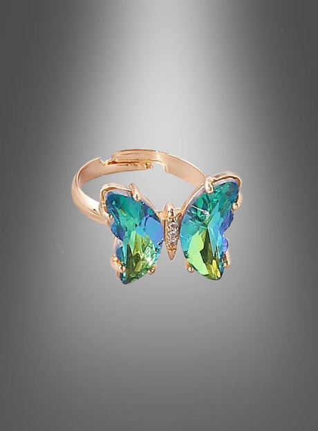 Wir präsentieren den „Verstellbaren Schmetterling-Ring aus Glas“ – einen goldenen Ring, der mit einem schmetterlingsförmigen Mittelstück verziert ist, auf dem blaue und grüne Edelsteine vor einem grau abgestuften Hintergrund zur Geltung kommen. Dieses exquisite Stück Glas-Schmetterling-Schmuck ist perfekt für Damen, die Wert auf elegante und einzigartige Accessoires legen.