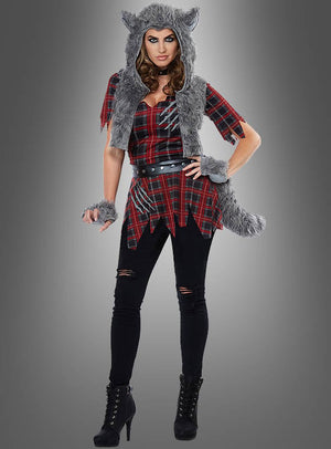 Eine Person, gekleidet in ein rotes Karohemd, eine schwarze Hose und schwarze Stiefel, ergänzt durch eine graue, pelzige Wolfskapuze, einen Schwanz und Armbänder – ein perfektes Wolfskostüm für Damen –, steht vor einem grauen Hintergrund.