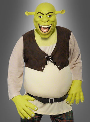 Eine Person, die das Shrek-Ogerkostüm für Erwachsene trägt – bestehend aus einer grünen Maske mit Oger-Ohren, einer braunen Weste, einem weißen Hemd, einem Gürtel und einer karierten Hose –, steht vor einem grauen Hintergrund mit Farbverlauf.