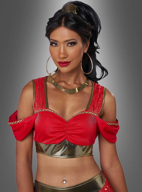 Eine Frau mit langen, dunklen Haaren, die zu einem hohen Pferdeschwanz zusammengebunden sind, trägt das „Bauchtänzerin Sarafina“-Damenkostüm – ein rot-goldenes orientalisches Bauchtanzkostüm – sowie große Creolen und eine metallische Halskette und steht vor einem grauen Hintergrund.