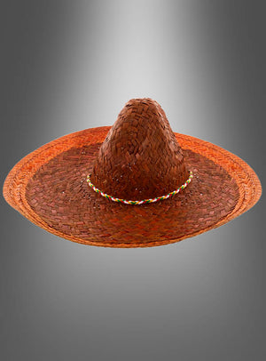 Der „Mexikaner Hut Sombrero Unisex“ ist ein brauner, geflochtener Strohhut mit breiter Krempe und einem bunten Zierband, abgebildet vor einem grauen Hintergrund mit Farbverlauf – ideal als krönender Abschluss Ihres Amigo-Kostüms oder als authentisches Accessoire.