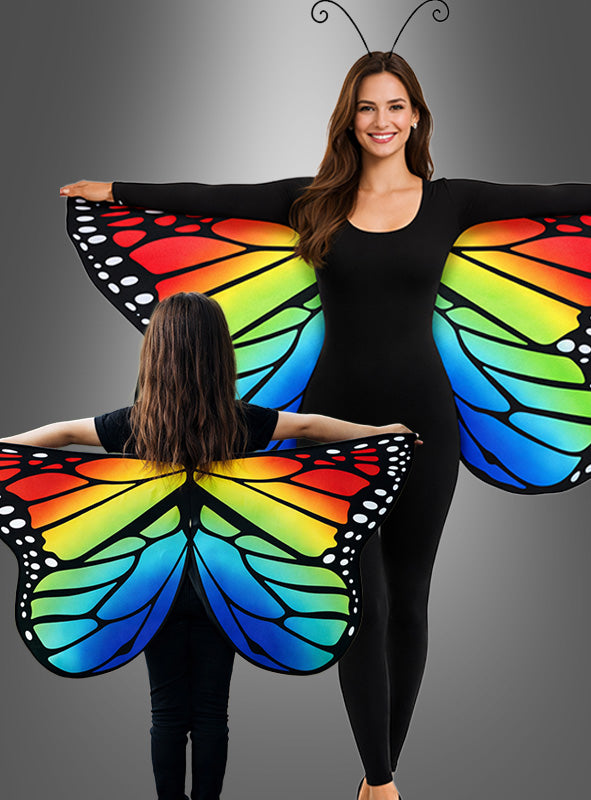 Zwei schwarz gekleidete Personen präsentieren die „Bunte Schmetterlingsflügel“ (beidseitig bedruckt) mit lebhaften Mustern und nehmen vor einem grauen Hintergrund auffällige, verspielte Posen ein – eine ideale Wahl als Karnevalsaccessoire oder Kinderkostüm.