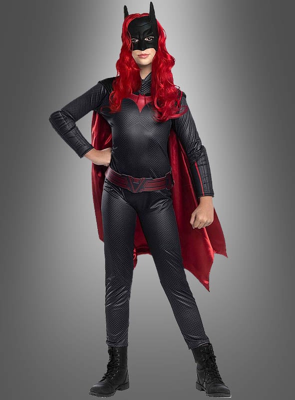 Eine Person, die das Original-Batwoman-Arrow-Kinderkostüm trägt – bestehend aus einem roten Umhang, einer roten Perücke, einer schwarzen Batman-Maske und schwarzen Stiefeln –, steht selbstbewusst vor einem grauen Hintergrund.