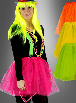 Eine Person mit einer neongelben Perücke, einem Regenbogenhut, grünen Hosenträgern, einer Perlenkette, einem schwarzen Shirt und einem knallpinken Tüllrock im 80er-Jahre-Stil sowie einer rosa Brille; rechts sind drei farbenfrohe Tüllröcke im 80er-Jahre-Stil in verschiedenen Farben zu sehen – perfekt, um dein eigenes verspieltes Ballerina-Kostüm zu kreieren.