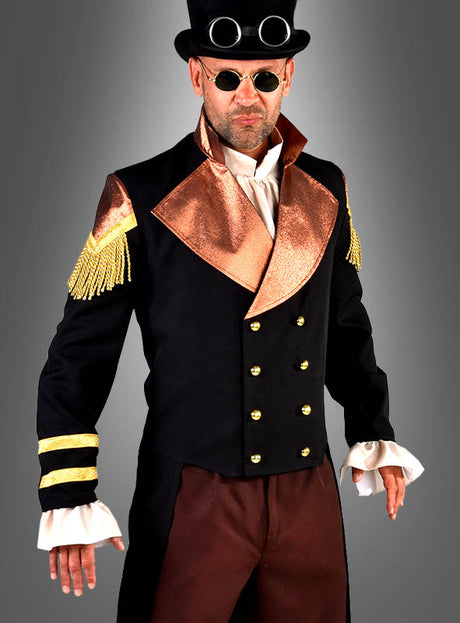 Ein Mann, der den „Steampunk Frack Emil“ trägt – einen viktorianisch inspirierten schwarzen Mantel mit metallischen Revers, goldenen Knöpfen und Schulterklappen, dazu eine braune Hose, einen Zylinder mit Schutzbrille und eine runde Sonnenbrille – perfekt für jedes viktorianische Kostüm oder als auffälliges Steampunk-Offiziers-Ensemble.