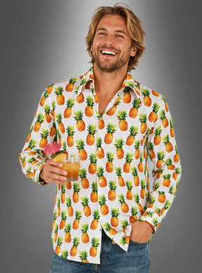 Ein lächelnder Mann in einem Hawaii-Party-Outfit – einem Ananas-Hemd – hält einen Cocktail mit einem Schirmchen in der Hand und steht vor einem grauen Hintergrund mit Farbverlauf.