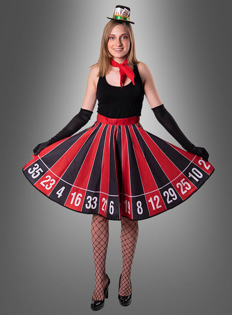 Vor einem grauen Hintergrund steht eine Frau, die als Casino-Glücksfee verkleidet ist. Sie trägt den Rock „Tellerrock Roulette Rad“, dazu schwarze Handschuhe, Netzstrümpfe, schwarze Pumps und einen kleinen Hut – die perfekte Kleidung für jede Las-Vegas-Mottoparty.